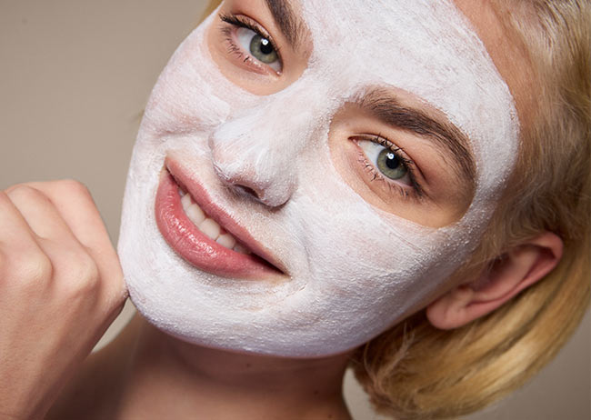 Person mit weißer Gesichtsmaske lächelt in die Kamera.