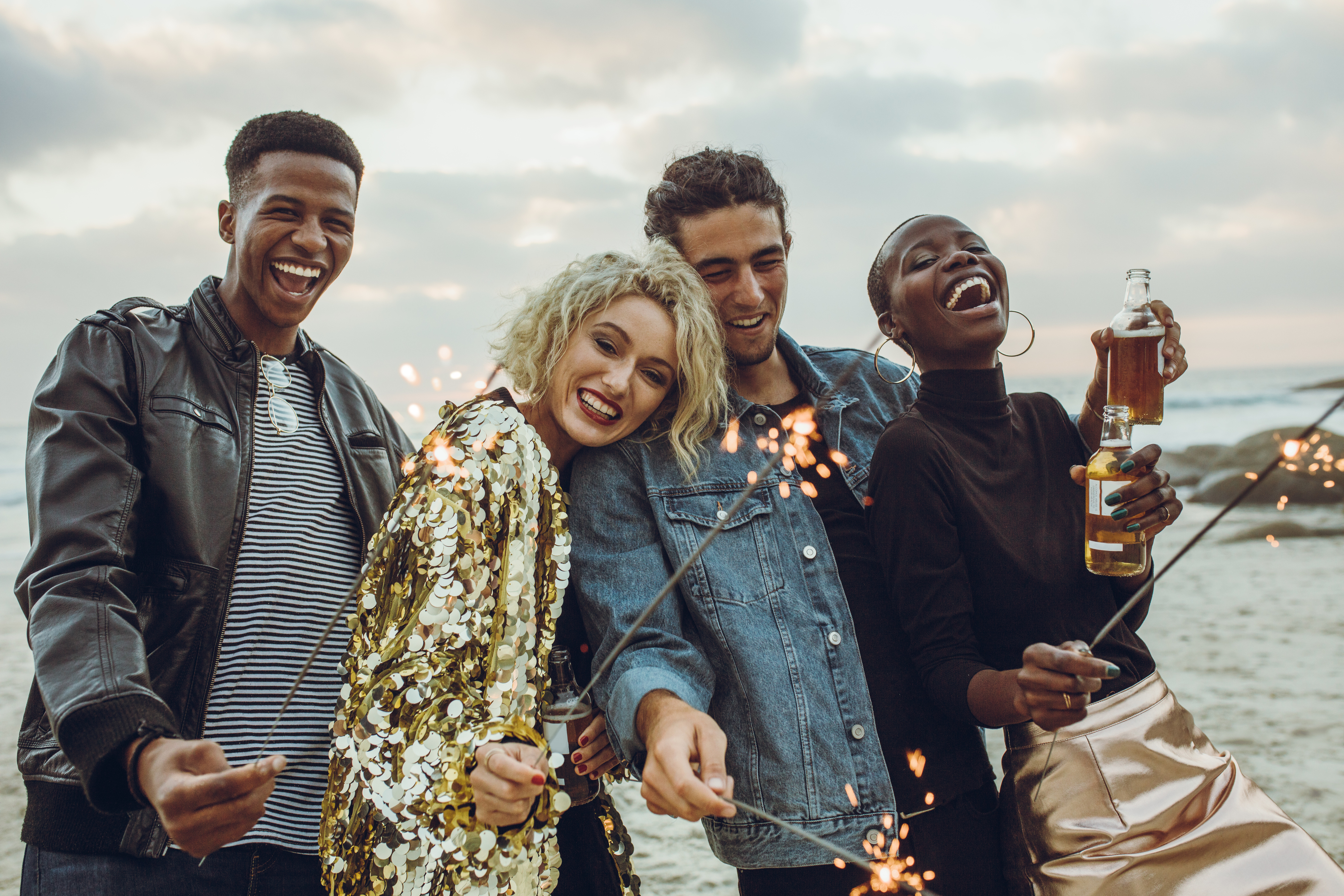 Group of friends celebrating with fireworks at beach schaebens-silvesterbräuche-friends