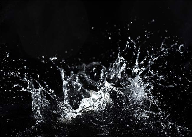 Wasser spritzt in alle Richtungen auf schwarzem Hintergrund.