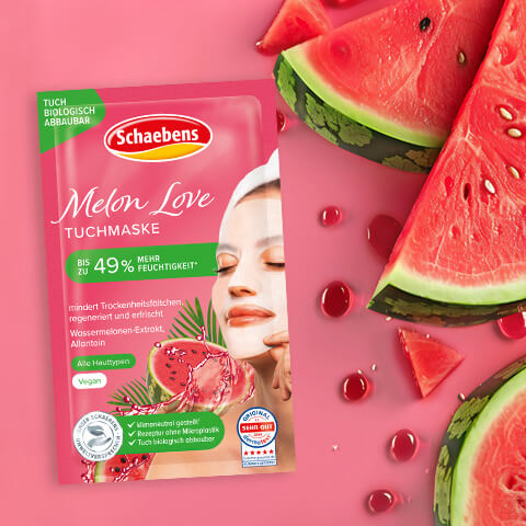Produktabbildung Schaebens Melon Love Tuchmaske auf rosa Hintergrund, daneben frische Wassermelonenscheiben.