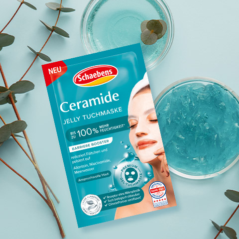 Packung einer Ceramide Jelly Tuchmaske von Schaebens auf blauem Hintergrund, umgeben von Eukalyptuszweigen und Gel in Schalen.