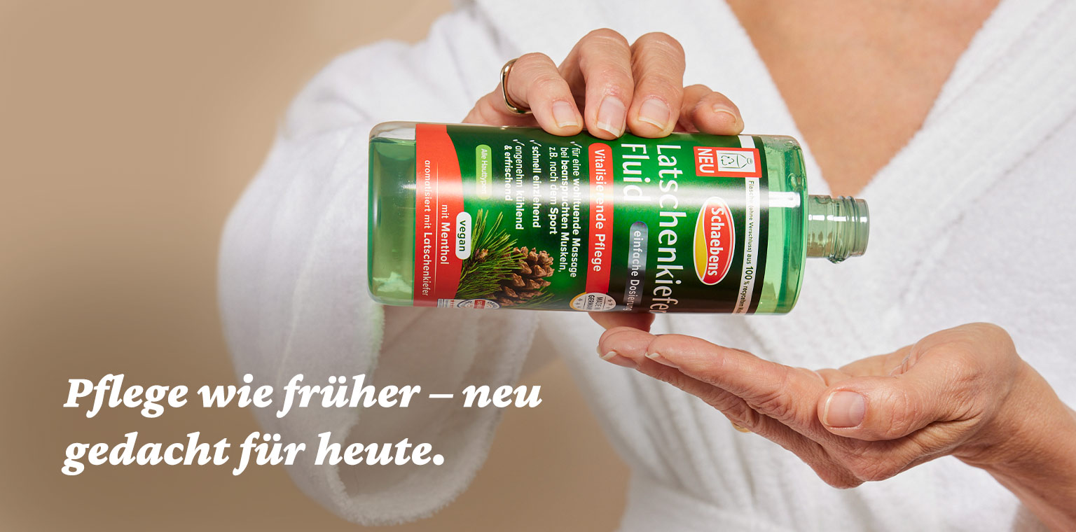 Person hält eine grüne Flasche Latschenkiefer-Fluid in der Hand, bekleidet mit weißem Bademantel. Text: Pflege wie früher – neu gedacht für heute.