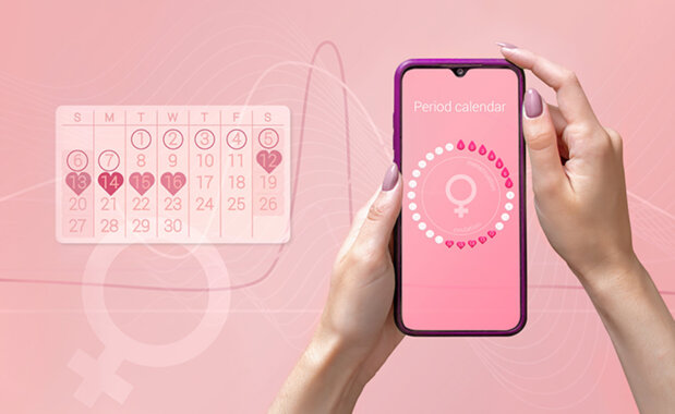Eine Hand hält ein Smartphone mit Menstruationskalender-App, daneben ein Monatskalender auf rosa Hintergrund.