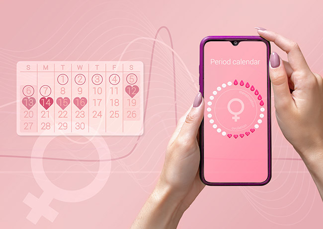 Eine Hand hält ein Smartphone mit Periodenkalender-App vor rosa Hintergrund, daneben ein Kalender mit hervorgehobenen Tagen.