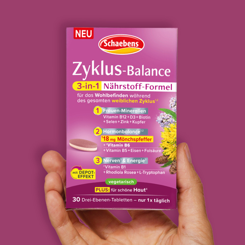 Eine Hand hält eine Packung Schaebens Zyklus Balance vor lila Hintergrund