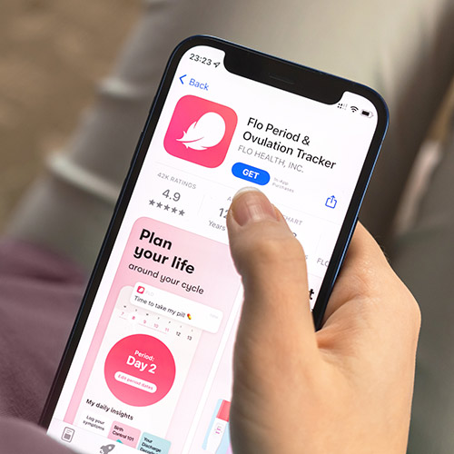Zyklus Tracking Apps Eine Hand hält ein Smartphone, das den Flo Period & Ovulation Tracker im App Store zeigt.