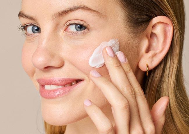 Eine Blonde Frau wendet die Retinol Creme Maske an