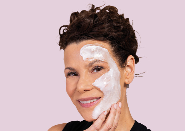 Gesichtshälfte einer Frau mit der Creme Maske eingecremt