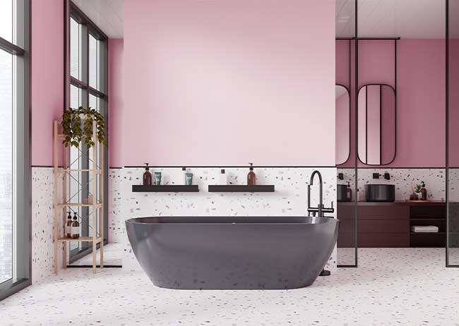 Mittig steht eine Badewanne einem rosa/ weißen Badezimmer.